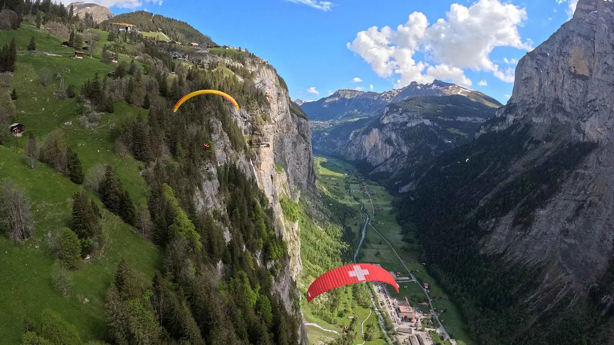 Tandem paraglider soaring above the Lauterbrunnen valley cliffs on a paragliding flight from Mürren