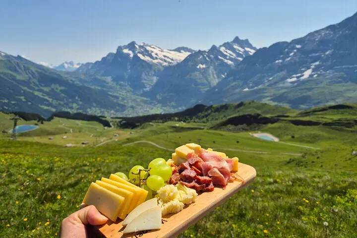 Guide pointing out mountain views during a cheese tasting walk above Männlichen near Lauterbrunnen