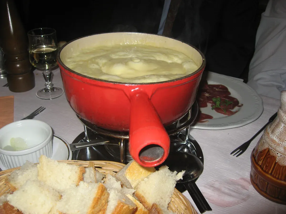 A pot of melted Swiss cheese fondue with bread cubes, the classic dish served in the Lauterbrunnen valley