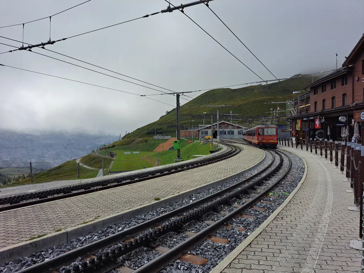 A red Jungfrau Railway train arriving at Kleine Scheidegg station platform, Switzerland