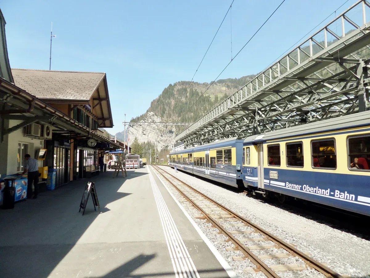 A Berner Oberland-Bahn train at the platform of Lauterbrunnen train station beneath the valley walls