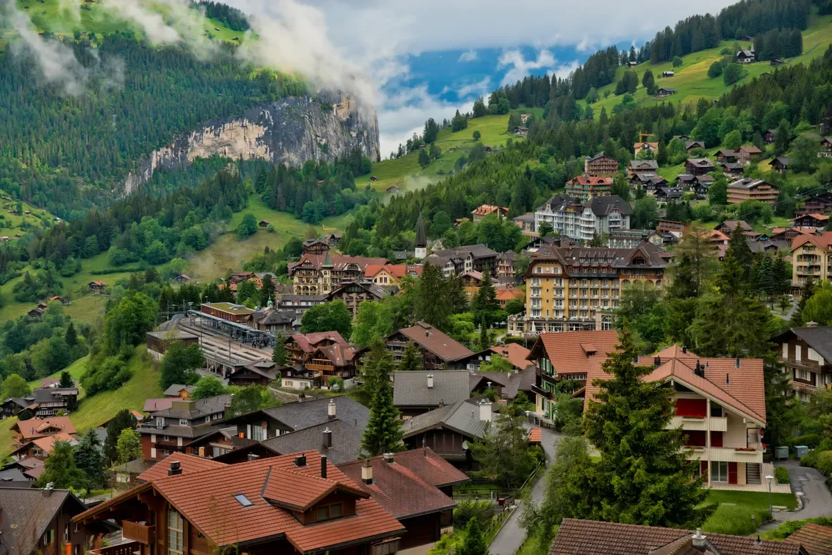 Wengen village on its sunlit ledge above the Lauterbrunnen valley, Switzerland, seen from the train